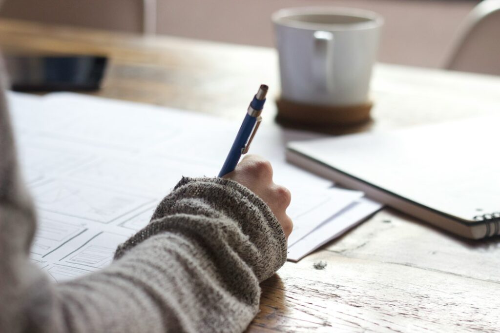 Person writing in a notebook at a desk, representing reflection, personal responsibility and purposeful action