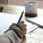 Person writing in a notebook at a desk, representing reflection, personal responsibility and purposeful action